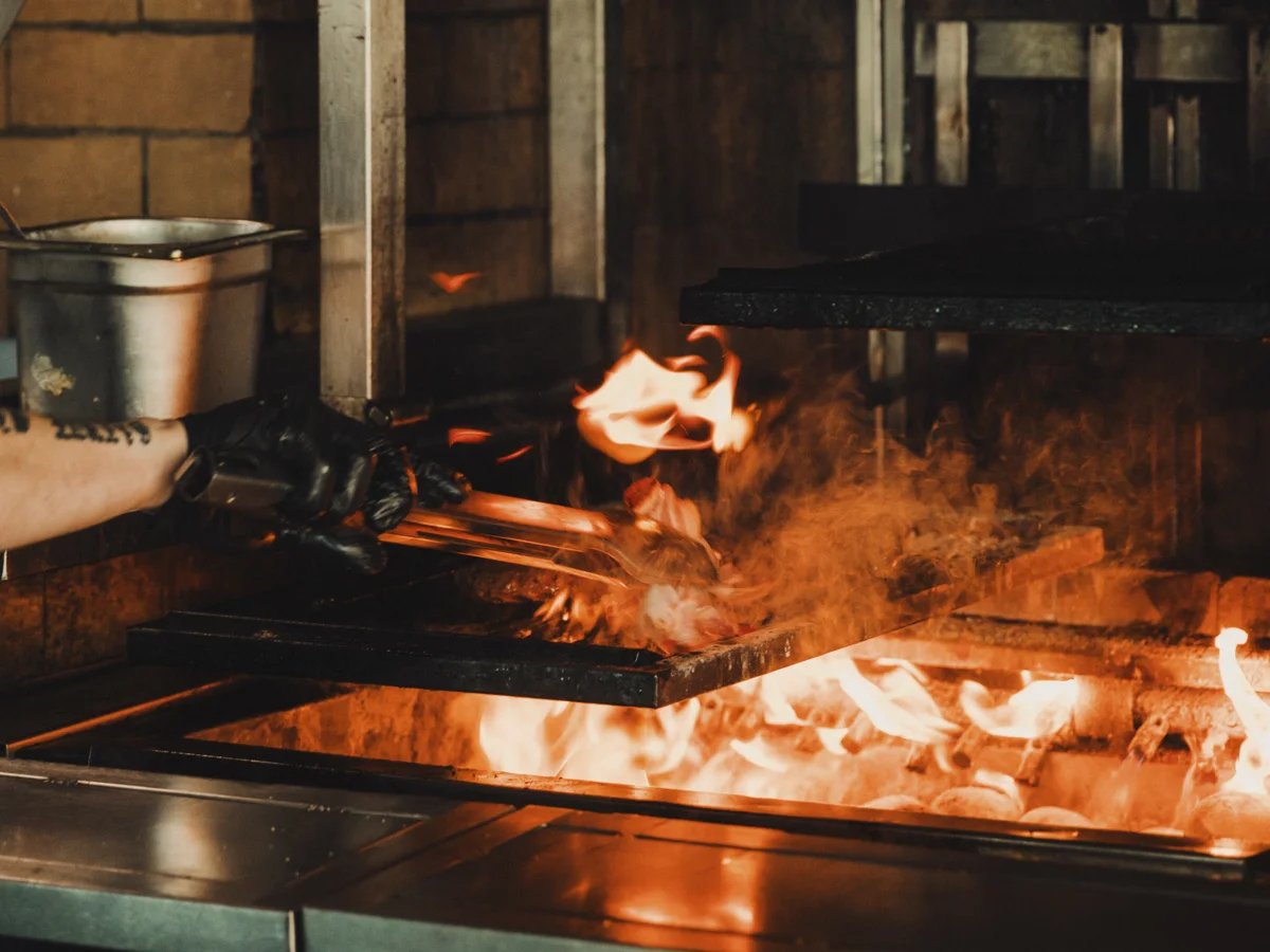 Chef cooking steaks on Ryleigh's Rooftop Steakhouse open grill