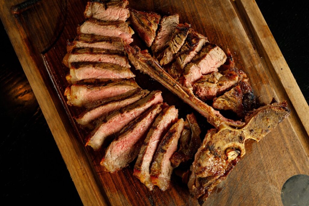 Sliced dry-aged porterhouse on a wooden sharing board at FIRE Steakhouse & Bar